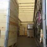 wooden crates stacked and secured inside a partially loaded truck trailer